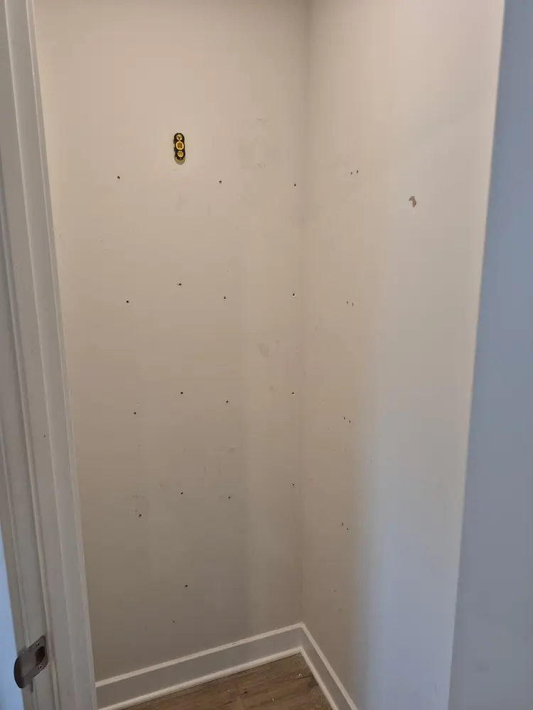 Empty pantry closet with bare drywall and old anchor holes, before work