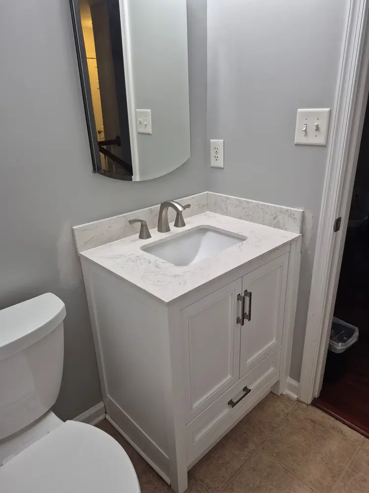 Finished powder room vanity with quartz top and brushed nickel faucet